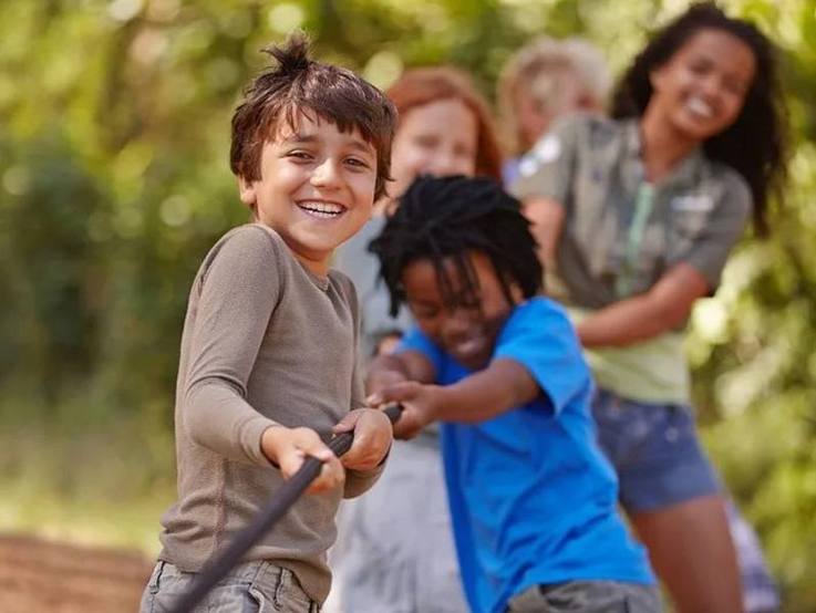 Fröhliche Kinder beim Tauziehen in der Natur