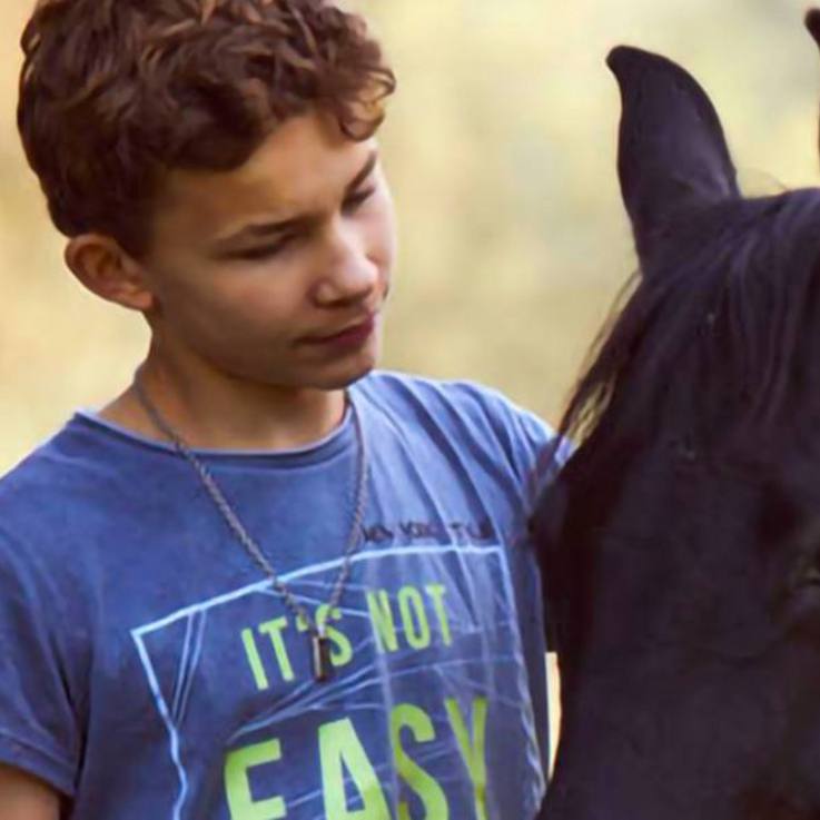 Junge und Pferd - einander zugewandt - auf dem Gelände der Paulihof Kinderhilfe gGmbH in Kühbach/Unterbernbach
